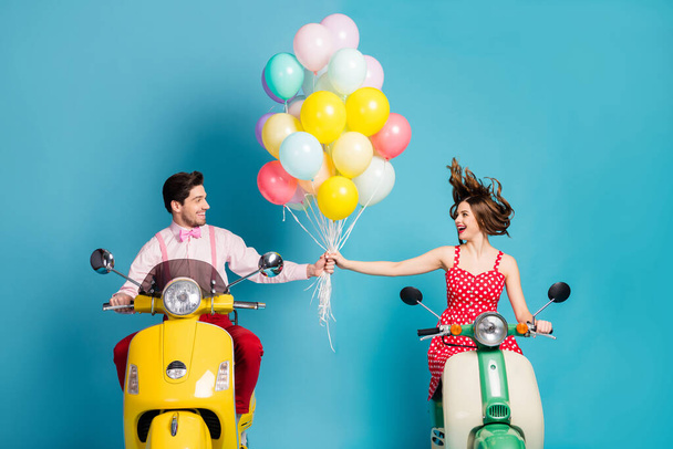 Photo of funny two people lady guy drive retro moped travelers hold hands many air balloons birthday guests good mood romantic atmosphere vintage clothes isolated blue color background - Foto, immagini