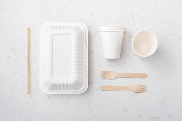 Környezetbarát élelmiszer csomagolás doboz, csésze, evőpálcika és villa fehér kvarc háttér, lapos laikus - Fotó, kép
