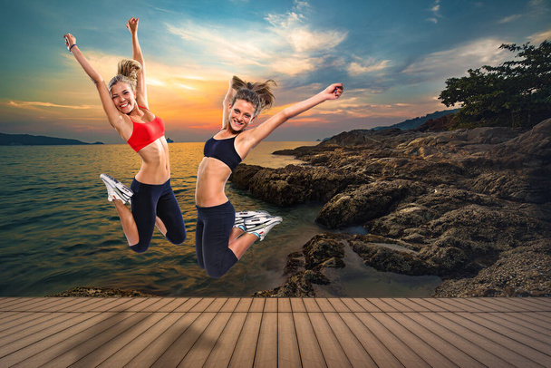 rubias, chicas de fitness de belleza, saltando alto desde un suelo de madera frente a un paisaje de isla tropical
 - Foto, Imagen