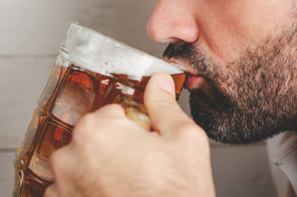 Ausschnittporträt eines bärtigen Mannes, der Bier trinkt. Alkoholismus-Konzept - Foto, Bild