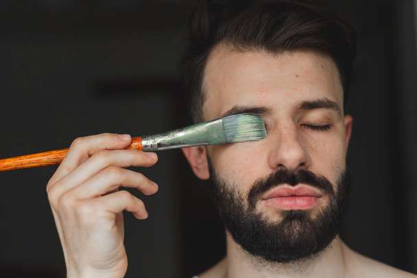 portrait of a bearded man holding artistic tools and preparing to paint a picture - Fotoğraf, Görsel
