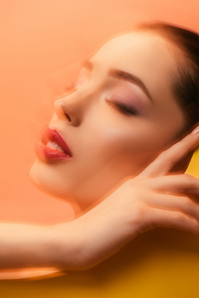 blurred image of beautiful woman with closed eyes in yellow paper circle hole - Фото, изображение