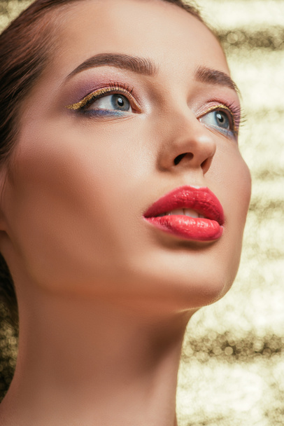 portrait of beautiful woman with shiny makeup looking away on golden background  - Fotografie, Obrázek