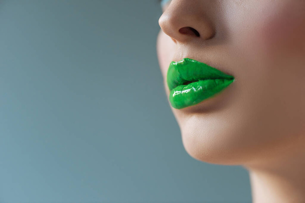 cropped view of woman with green lips isolated on blue - Fotoğraf, Görsel