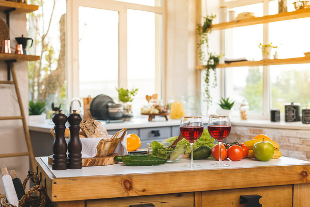 Punaviini, lasit ja terveellinen ruoka pöydällä modernissa keittiössä. Koti sisustus.  - Valokuva, kuva