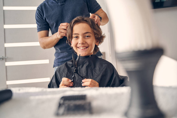 Little cute boy smiling while getting new hairstyle - Фото, изображение