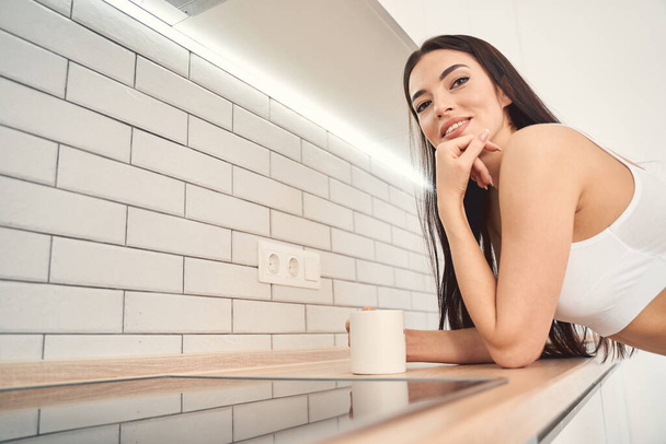 Pretty young lady resting on kitchen worktop - Photo, image