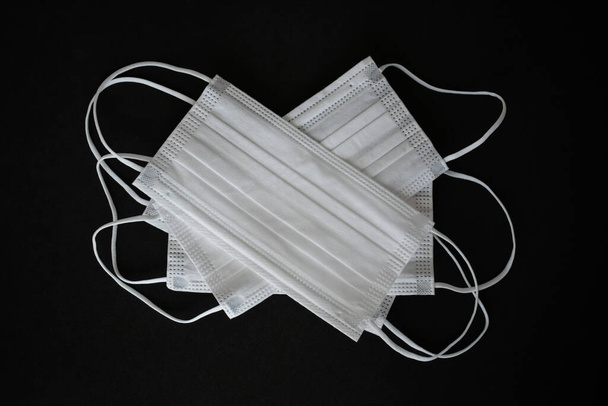 Білі хірургічні маски, сфотографовані на чорному тлі
 - Фото, зображення
