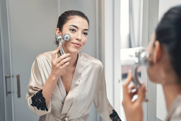 Pleasant nice-looking young woman taking care of her skin at morning - 写真・画像
