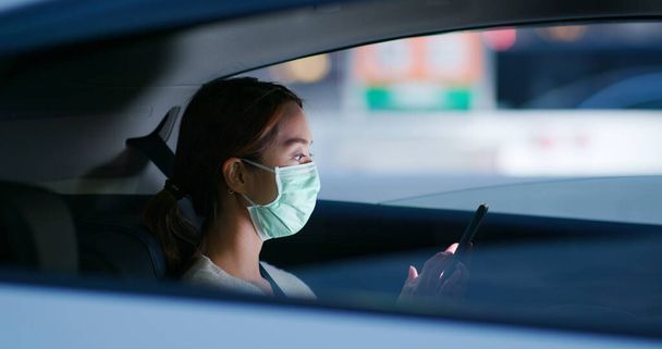 Woman wear medical mask and use of mobile phone sit inside the car - Photo, Image