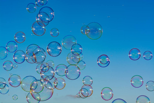 Hintergrund mit vielen Seifenblasen in der Luft, blauem Himmel, Outdoor-Spaß für alle - Foto, Bild