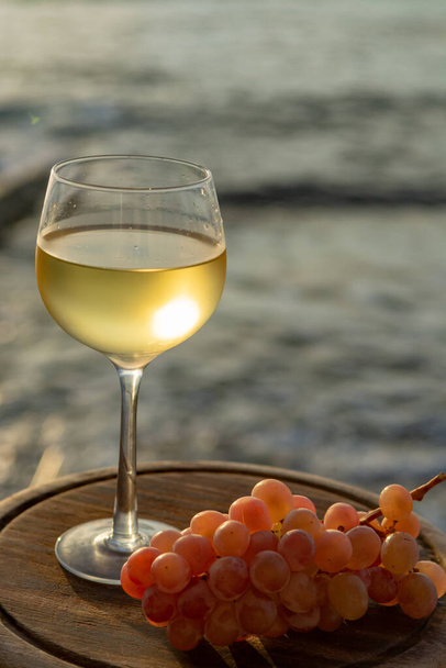 Aperitivo vinho branco frio servido em copos com uvas rosa na tessace ao ar livre witn vista mar de perto
 - Foto, Imagem