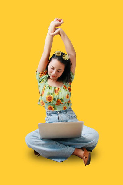 Asian women are happy and beautiful stretching while working with laptop computers isolated on yellow background - Foto, Imagem