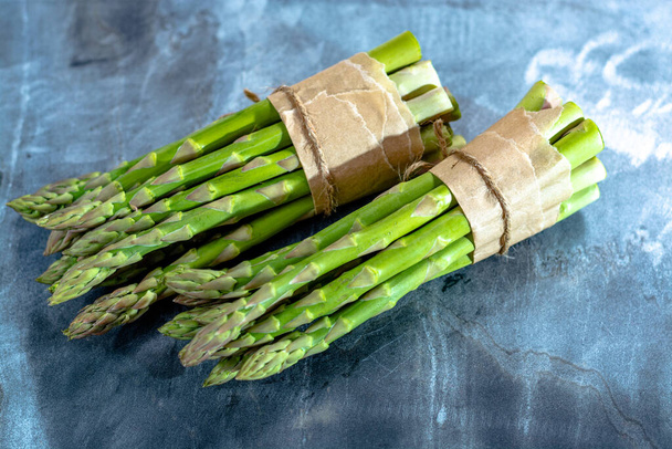 Fresh raw green asparagus vegetable on grey marble board close up - 写真・画像