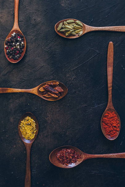 Various spices in wooden spoons on old black table - Foto, imagen