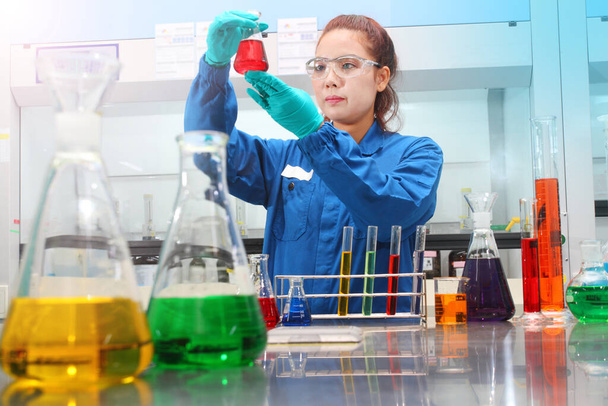 Mujer joven probando solución análisis químico laboratorio química industria
 - Foto, Imagen