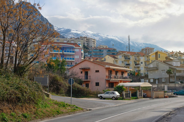 Зимовий день у Чорногорії. Вид на місто Доброта, розташоване біля підніжжя засніжених гір. - Фото, зображення