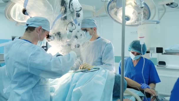 χειρουργοί εκτελέσει μια χειρουργική επέμβαση και να εξετάσουμε μέσα από ένα μικροσκόπιο - Πλάνα, βίντεο