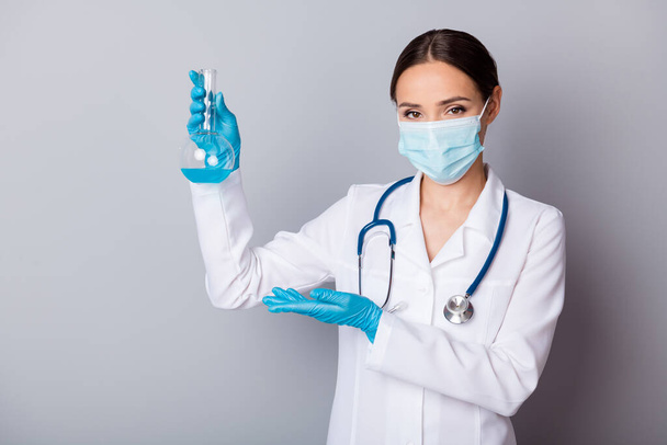 Photo of virologist doc lady experienced professional hold test flask tube examining vaccine showing project wear gloves facial mask uniform lab coat stethoscope isolated grey background - Photo, image