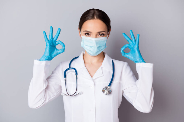 Photo of attractive virologist doc experienced professional showing okey symbols hands answer patient examination results wear medical uniform lab coat stethoscope isolated grey background - Fotó, kép
