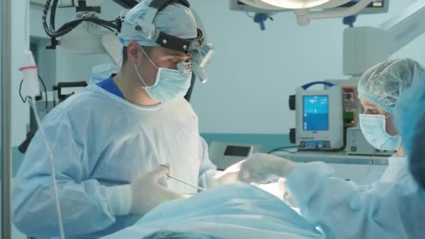kirurgi ompelee viillon potilaalle leikkauksen aikana - Materiaali, video