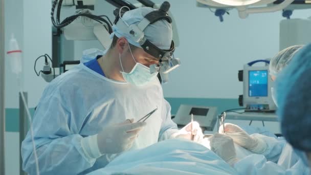 kirurgi ompelee viillon potilaalle leikkauksen aikana - Materiaali, video