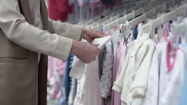 liefdevolle moeder koopt kleding voor haar pasgeboren baby van delicate breigoed - Video