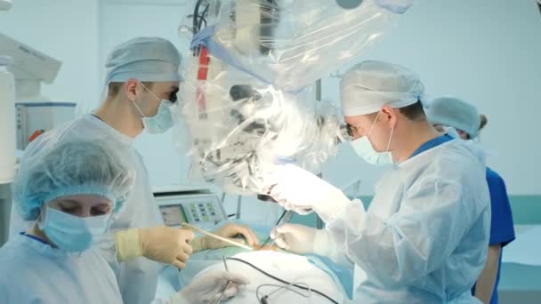 χειρουργοί εκτελέσει μια χειρουργική επέμβαση και να εξετάσουμε μέσα από ένα μικροσκόπιο - Πλάνα, βίντεο
