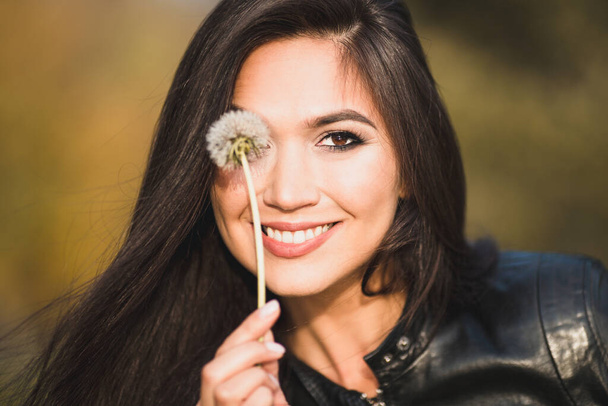 Attractive seductive sexy brunette with a charming smile with a dandelion near her eye - Fotografie, Obrázek