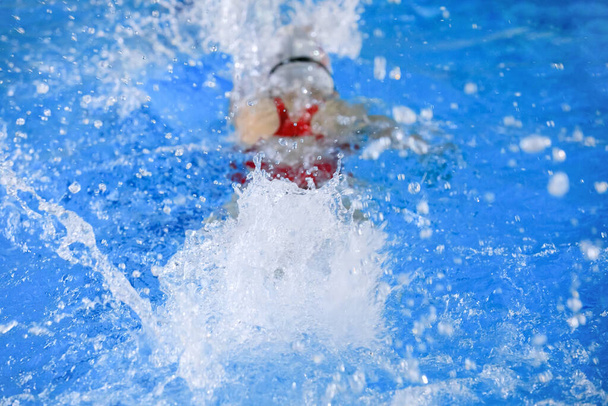 Zwemmende vrouw in zwembad met blauw water. - Foto, afbeelding