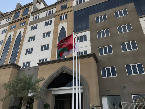 Μπροστά είσοδος του Fraser Suites muscat oman υποκατάστημα με φοίνικα και τις δύο πλευρές και σημαίες της χώρας και ξενοδοχεία - Φωτογραφία, εικόνα