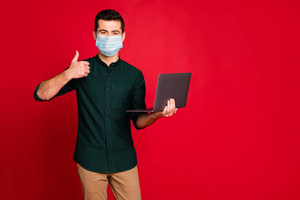 Portrait of his he nice attractive guy wearing safety mask using laptop showing thumbup stop cov ncov influenza infection prevention isolated bright vivid shine vibrant red color background - Φωτογραφία, εικόνα