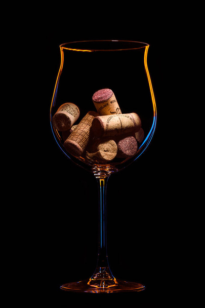 wine corks in a glass on a black background - Фото, изображение