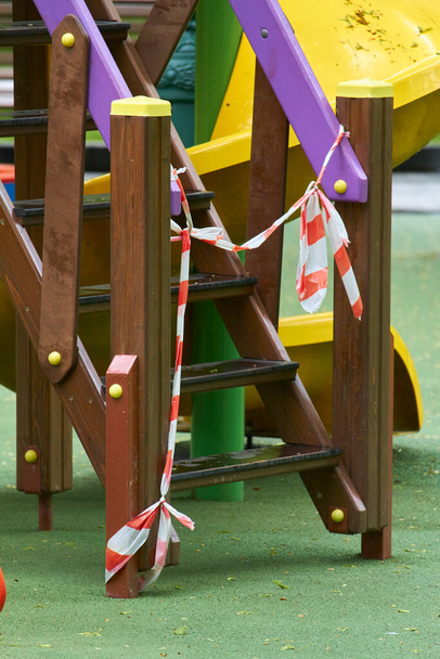Leerer Spielplatz ohne Kinder mit rot-weißem Warnstreifen, Einschränkungen für Covid19 Coronavirus - Foto, Bild