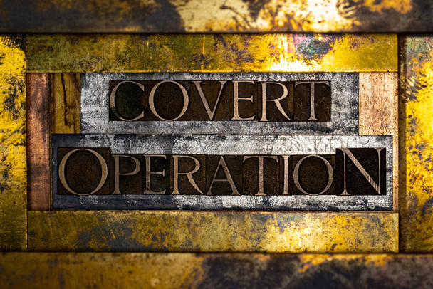Photo of real authentic typeset letters forming Covert Operation text on vintage textured silver grunge copper and gold background - Photo, Image