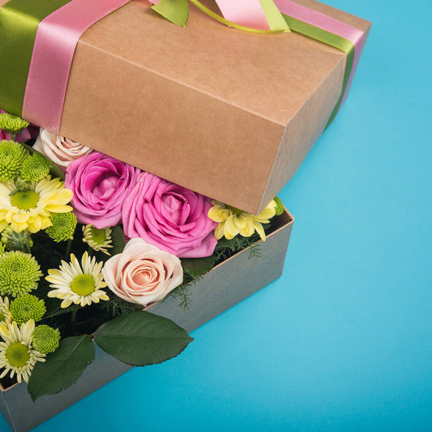 όμορφη συσκευασία δώρου με λουλούδια. αξεσουάρ διακόσμησης γάμου. μπλε φόντο - Φωτογραφία, εικόνα