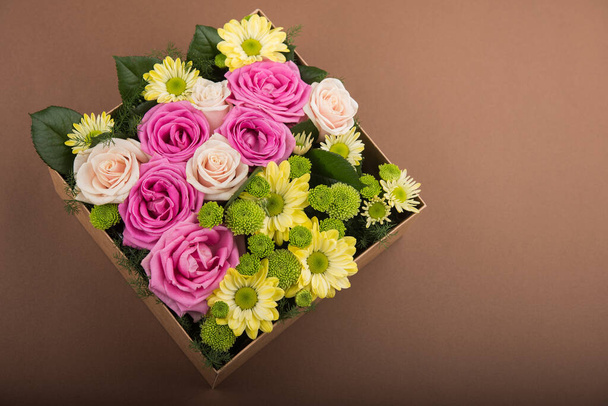 Gift box with flowers on vintage brown background - Fotó, kép