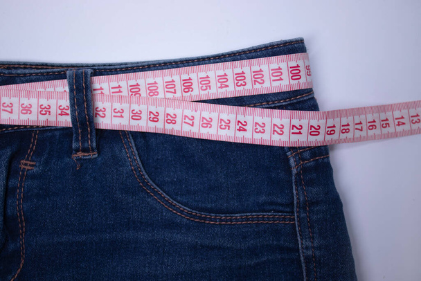 пара джинсів з мірною стрічкою замість пояса. Концепція дієти та втрати ваги
. - Фото, зображення