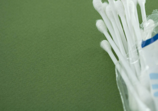 Des bâtons d'oreille en plastique de coton dans le pack transparent démarré sur un fond texturé vert. Modèle de bannière avec espace de copie. Bâtonnets de coton biologique pour l'auto hygiène. Concept de soin des oreilles pour l'hygiène
. - Photo, image