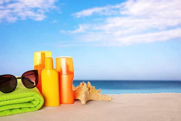 Set of sun protection products and stylish sunglasses on sandy beach. Space for text - Foto, imagen