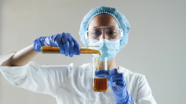 化学実験室のシーン:魅力的な若い博士課程の学生の科学者は、ガラス管内のエンジンオイルや蜂蜜を観察. - 映像、動画