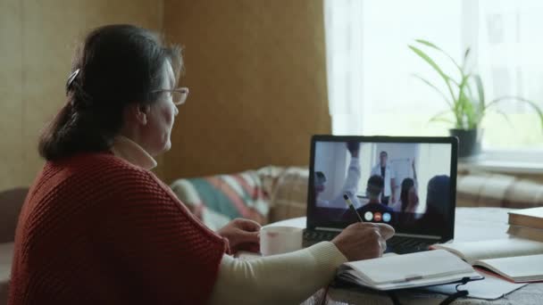 etäopetus, moderni isoäiti käy läpi etäopetuksen konferenssin aikana verkossa videopuhelun avulla kannettavalla tietokoneella - Materiaali, video