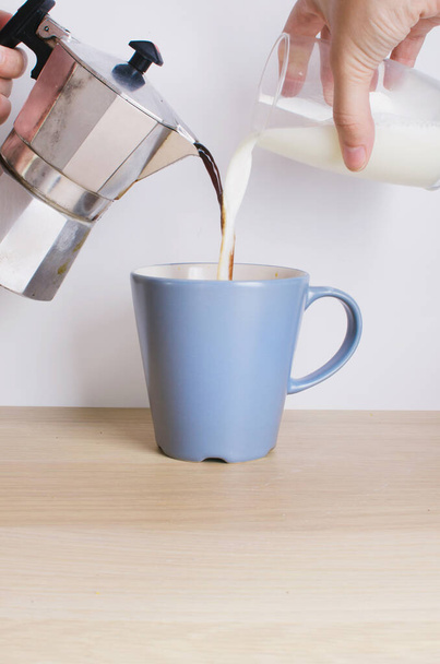 Italiaans koffiezetapparaat. koffie en melk in de beker doen - Foto, afbeelding
