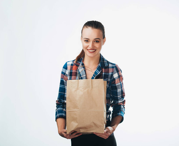 Young woman is holding grocery shopping bag on white background. Young girl is looking in camera. Isolated background. Closeup. - Foto, Bild