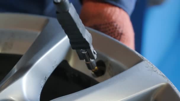 Close-up of male hands installing new nipple on the wheel disk of a car - Materiaali, video