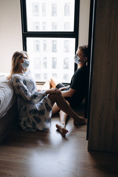 Мужчина и девушка сидят на полу в масках на лицах
 - Фото, изображение