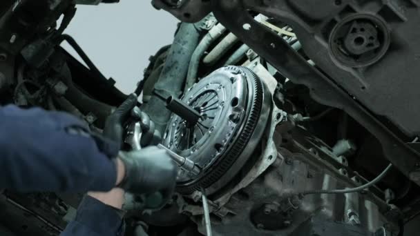 Auto mechanic in protective working gloves, unscrews the clutch pressure plate under the car engine - 映像、動画