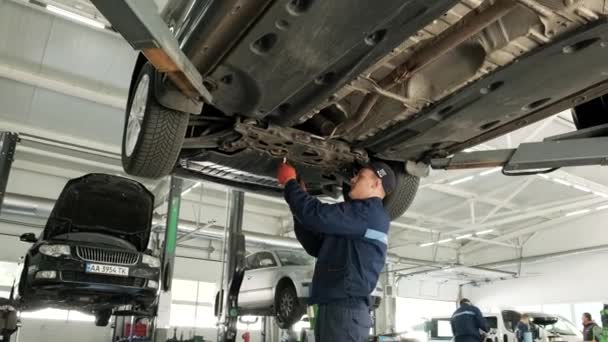 Auto mechanic working underneath car lifting machine at the garage. Auto repair shop, Car service, repair.    - Footage, Video