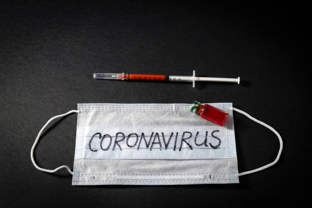 a syringe with blood and an ampoule with the result of a blood test for a new rapidly spreading nCOV - 2020 coronavirus originating from Wuhan, China on a black background - Φωτογραφία, εικόνα