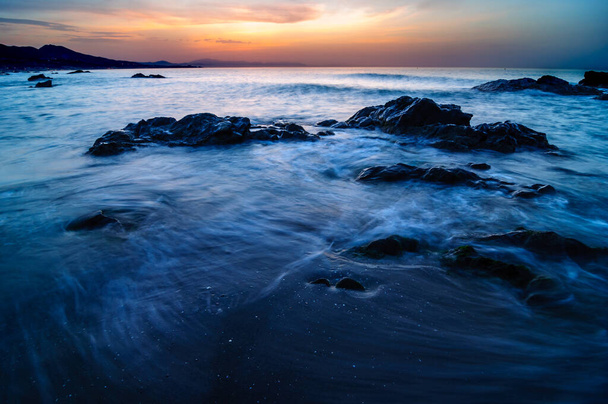 Sol, Mar e Nascer do Sol Rochoso. Paisagem impressionante de uma praia com longa exposição
 - Foto, Imagem